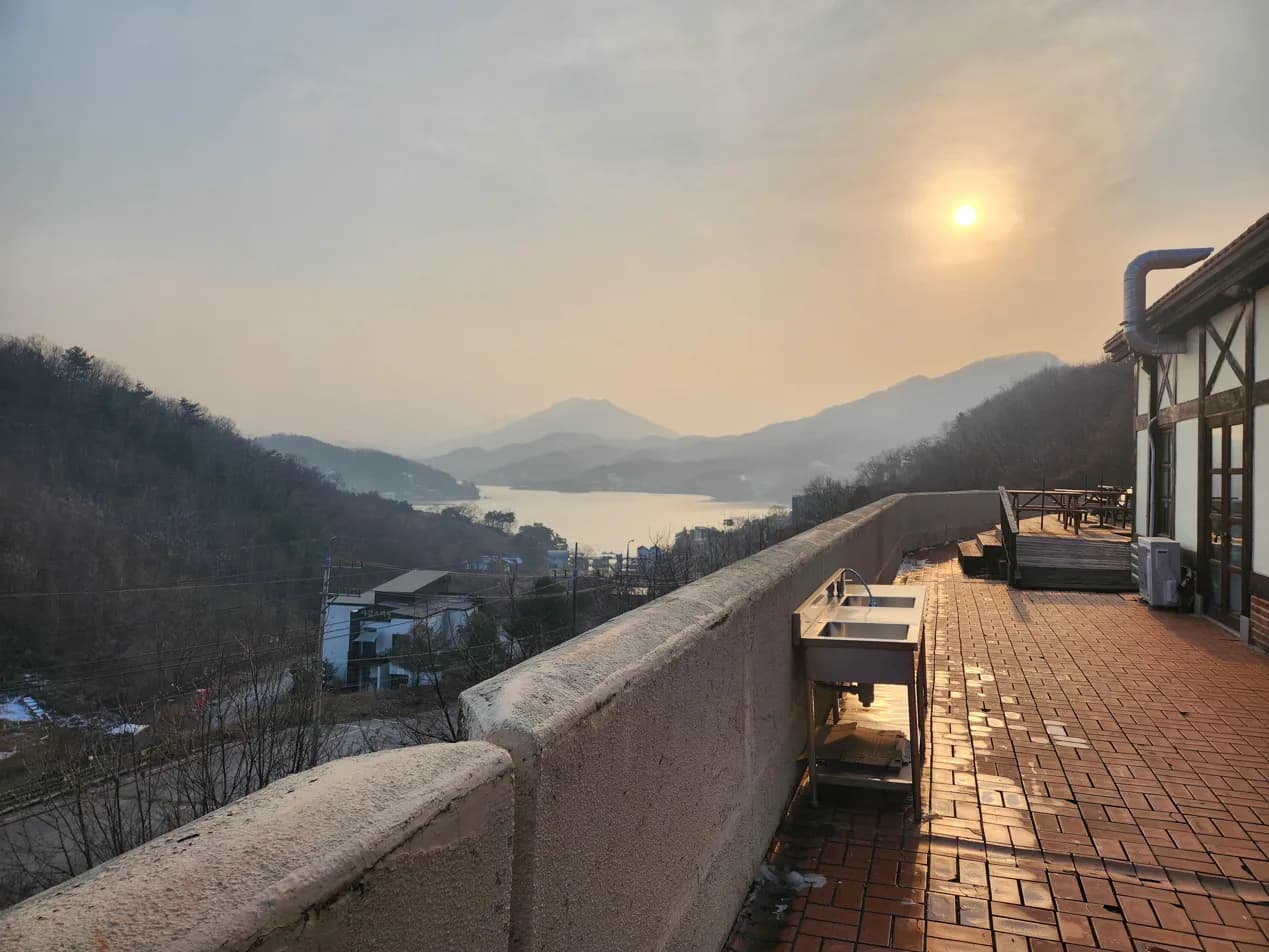 마을 언덕 위 테라스에서 해질녘에 바라본 청평호와 산 능선
